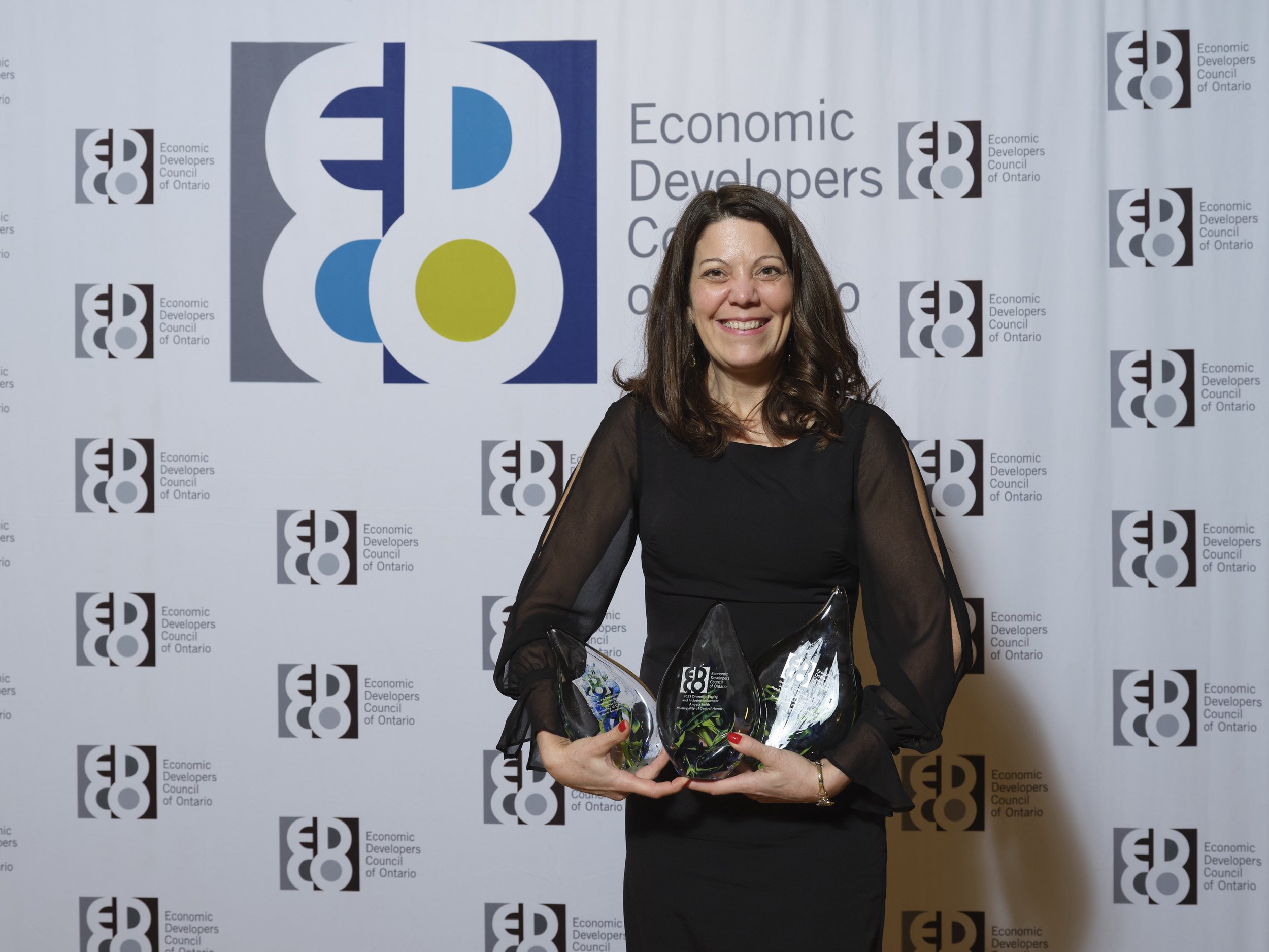 Community Improvement Coordinator Angela Smith holding three awards.