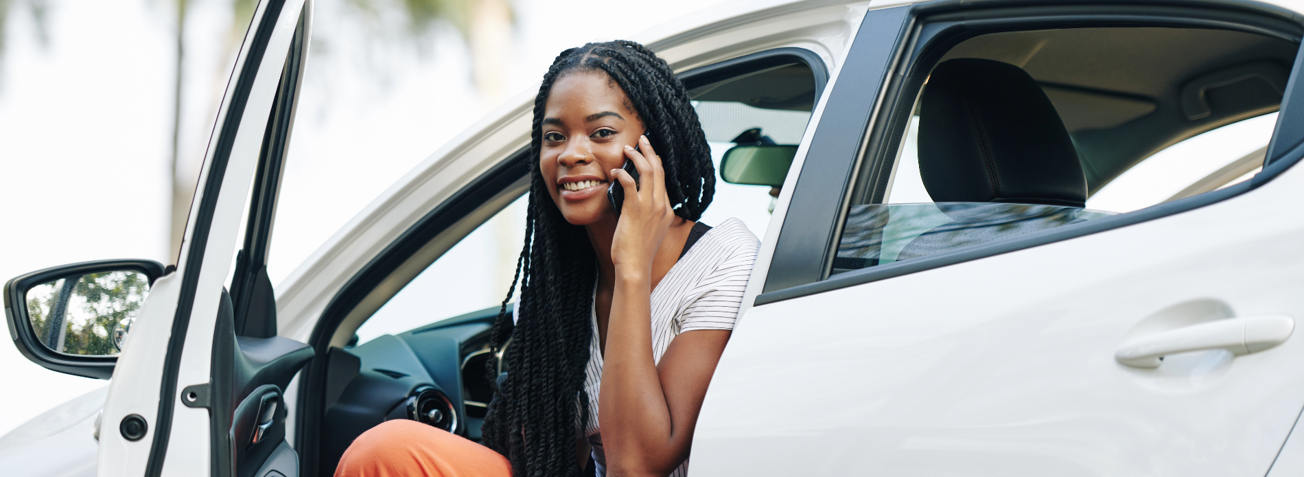 A woman getting out of the car, talking on her smart phone